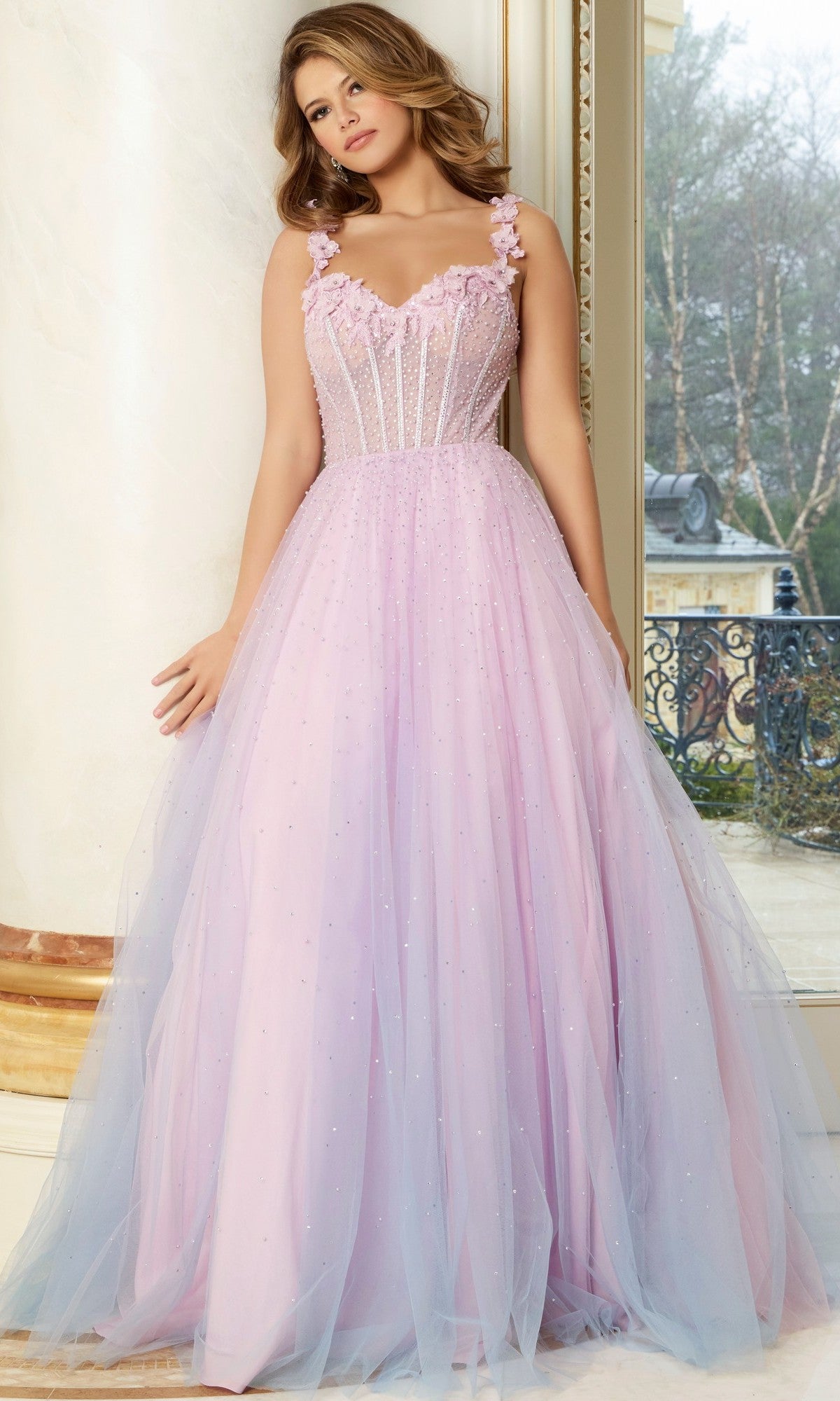 A woman stands indoors wearing the Jovani 47305 Long Prom Dress, a light purple, sleeveless, floor-length gown with 3D floral appliques on the straps and a fitted bodice.